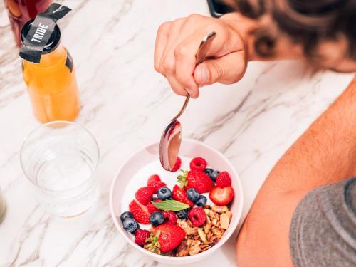 a woman eating a bowl of fruit with a spoon at Tribe Carcassonne in Carcassonne