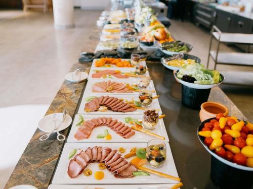 a long table full of plates of food with meats and vegetables at The Bodrum Hotel Yalıkavak - MGallery Collection in Yalıkavak