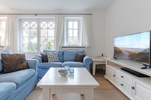 a living room with a blue couch and a tv at Wynkaat in Nieblum