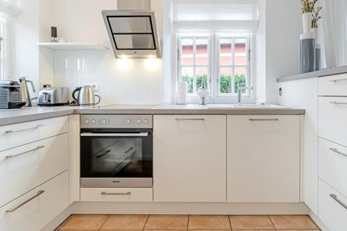 a kitchen with white cabinets and an oven at Wynkaat in Nieblum