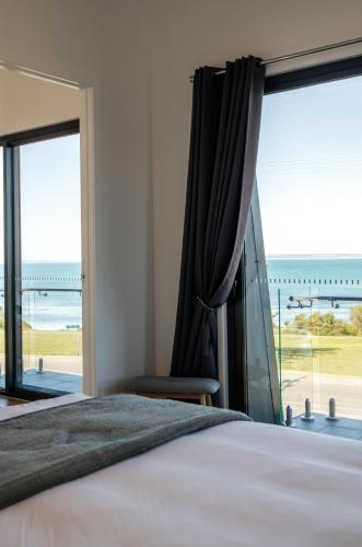 a bedroom with a bed and a large window at Fairy Wren in Kingscote