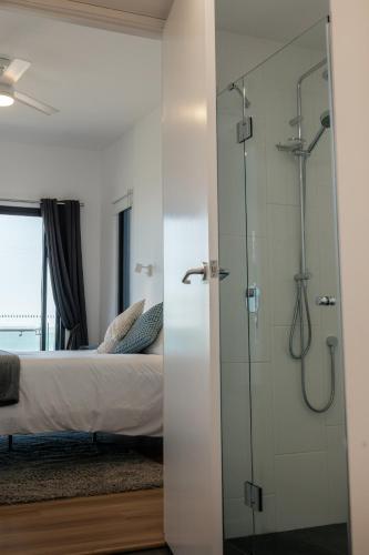 a glass shower in a bedroom with a bed at Fairy Wren in Kingscote