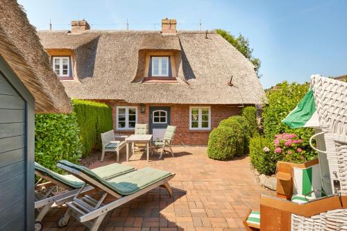 una casa con tetto di paglia e patio di Sanfte Brise 1- links a Oevenum