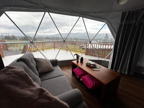 ein Wohnzimmer mit Couch und großem Fenster in der Unterkunft La cabaña de Ciela G glamping con jacuzzi y croquet in Latacunga