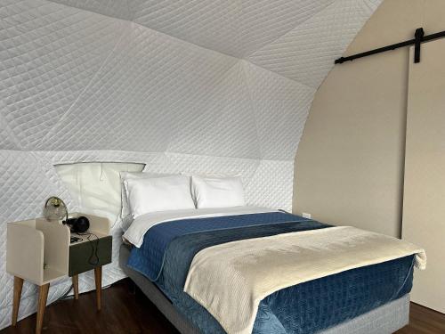 a bedroom with a bed with a white wall at La cabaña de Ciela G glamping con jacuzzi y croquet in Latacunga