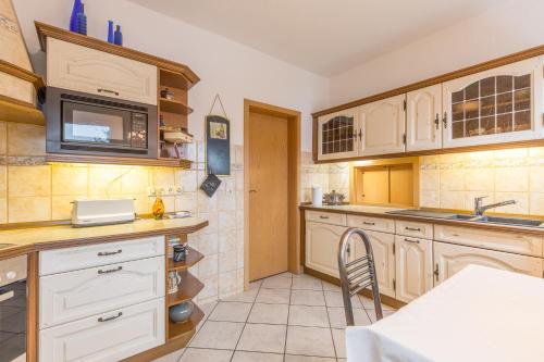 een keuken met witte kasten, een wastafel en een tafel bij Ferienwohnung Erika in Dassow