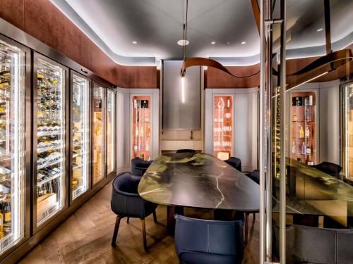 a dining room with a table and chairs and wine racks at Palazzo Tirso MGallery Cagliari in Cagliari