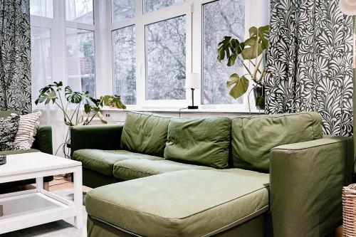 a living room with a green couch and windows at LichtLoft Pirna Altstadt mit 4 Schlafzimmer und XXL Wohnküche in Pirna