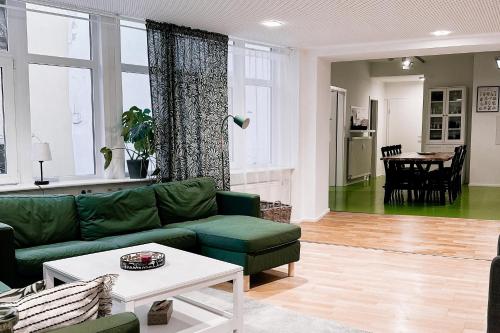 a living room with a green couch and a table at LichtLoft Pirna Altstadt mit 4 Schlafzimmer und XXL Wohnküche in Pirna