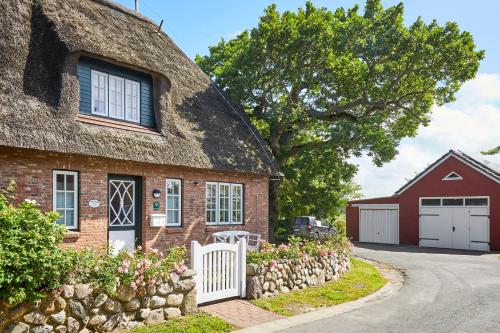 een stenen huis met een rieten dak en een witte poort bij Alte Eiche in Utersum