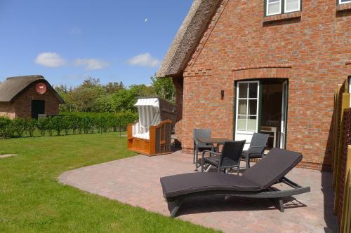 een patio met stoelen en een grill in de tuin bij Strandnest in Witsum