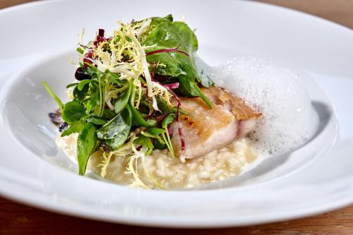a plate of food with a salad and fish on risotto at Hotel Zugspitze in Garmisch-Partenkirchen