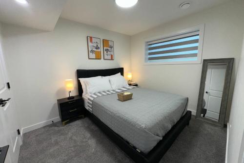 a bedroom with a bed and two lamps and a window at Sleek Guest Retreat SW EDM BSMT Suite in Edmonton