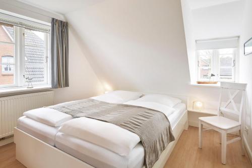 una camera da letto bianca con un letto e una sedia di Haus Kastanie a Boldixum