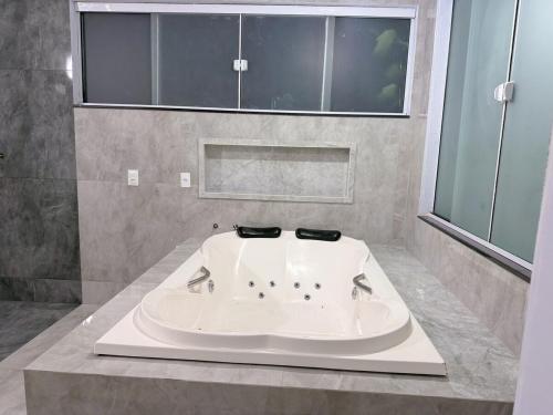 a large white bath tub in a bathroom at Recanto perto do mar com Jacuzzi in Camboriú