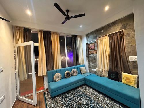 un canapé bleu dans un salon avec un ventilateur de plafond dans l'établissement Mangal Uday Villa, à Jaipur