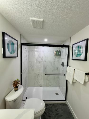 a white bathroom with a shower and a toilet at Sleek Guest Retreat SW EDM BSMT Suite in Edmonton