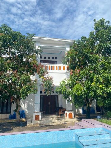a white house with a pool in front of it at Homestay loteng in Madasari