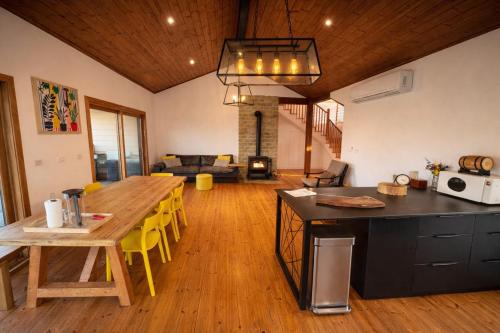 una cucina e un soggiorno con tavolo in legno e sedie gialle di Villa Gshur a Eli Ad