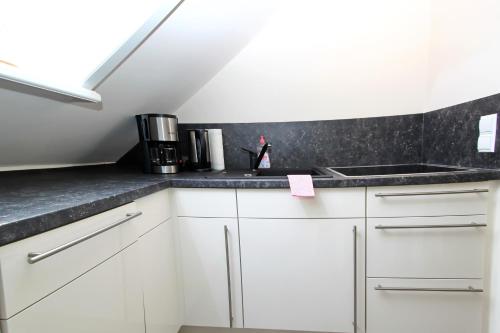 eine Küche mit weißen Schränken und einer Spüle in der Unterkunft Syltrose in Hörnum