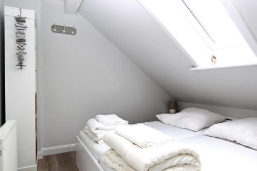 a white bedroom with white towels on a bed at Syltrose in Hörnum