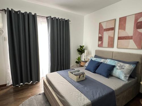 a bedroom with a bed with blue pillows and curtains at JeMeCa Suites in Kauswagan
