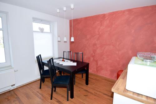 ein Esszimmer mit einem Tisch und einer roten Wand in der Unterkunft Wendstraße 10, Ferienhaushälfte in Heiligenhafen