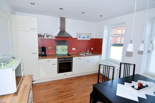 eine Küche mit weißen Schränken und einem Tisch mit Stühlen in der Unterkunft Wendstraße 10, Ferienhaushälfte in Heiligenhafen