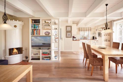 ein Esszimmer mit Tisch und Stühlen und einem Kamin in der Unterkunft Reethüs Maj - links in Utersum