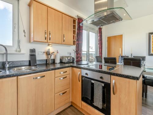 een keuken met houten kasten, een wastafel en een fornuis bij Beachview in Llanelli