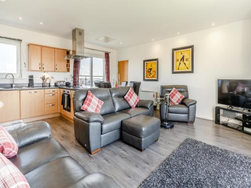 a living room with leather furniture and a kitchen at Beachview in Llanelli