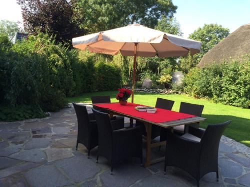 a table and chairs with an umbrella on a patio at FöhrEuch 2 in Borgsum