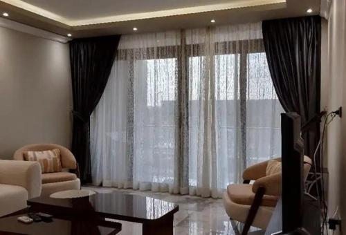 een woonkamer met een bank en een tafel en gordijnen bij elwadaayan waady in Riyad