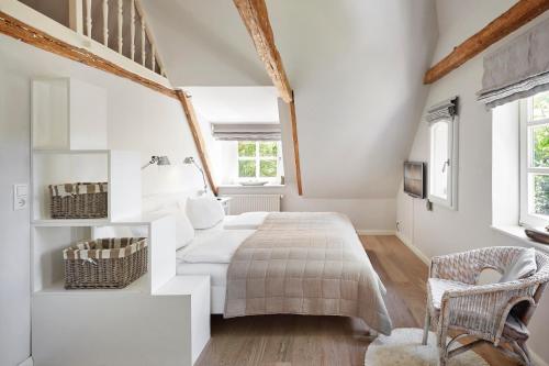 een witte slaapkamer met een bed en een stoel bij Haus Augenblick in Utersum