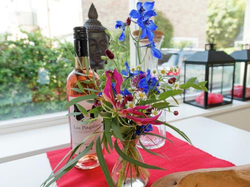 een fles wijn en een vaas met bloemen op een tafel bij Alluring Apartment in Bergen with Terrace, Garden and BBQ in Bergen