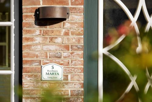 een bord aan de zijkant van een bakstenen gebouw bij Reethüs Marta - rechts in Utersum