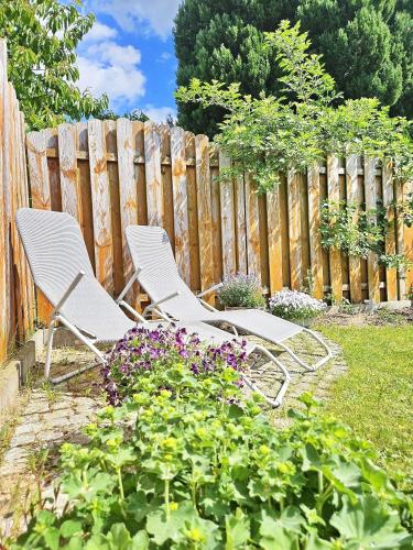 two white chairs sitting in a garden next to a fence at Ferienhaus Sommerwiese - ABC327 in Klein Warin