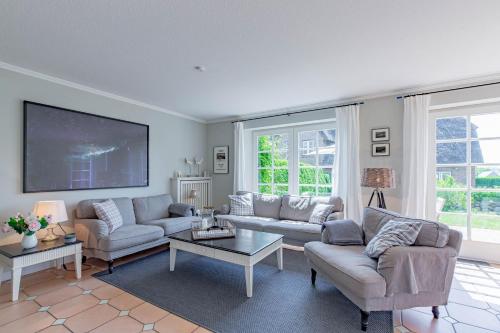 a living room with two couches and a tv at Reetdachhaus Hedehusum in Hedehusum