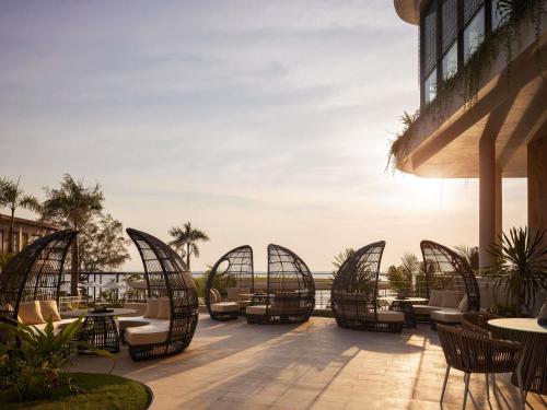 an outdoor patio with chairs and tables on a building at Novotel Sihanoukville Holiday Resort in Sihanoukville