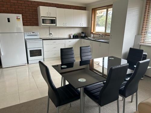 a kitchen with a dining room table and chairs at The little beach house in Tuross Heads