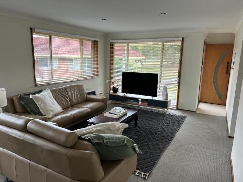 a living room with a couch and a flat screen tv at The little beach house in Tuross Heads