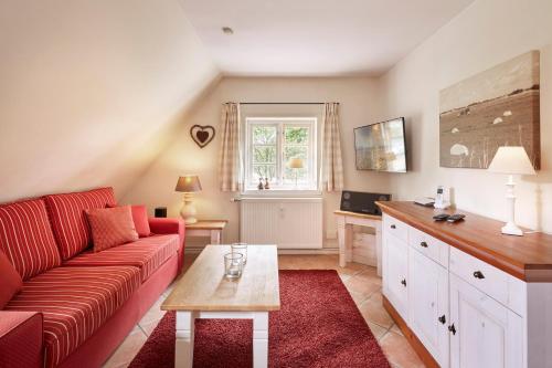 a living room with a red couch and a table at Entennest im Witthüs in Nieblum
