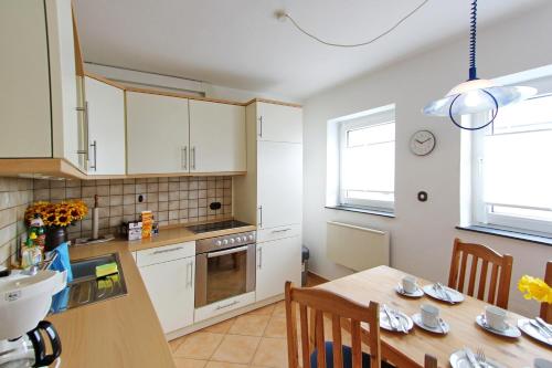 een keuken met witte kasten en een houten tafel bij Strandmuschel in Hörnum