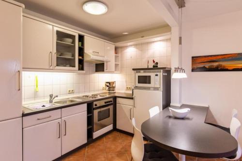 a kitchen with white cabinets and a table and a table and chairs at Stranddüne, D13 in Duhnen