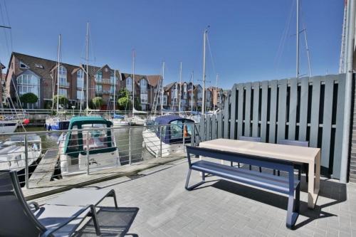 a bench and chairs sitting on a patio near a marina at City Marina, CM24d in Cuxhaven