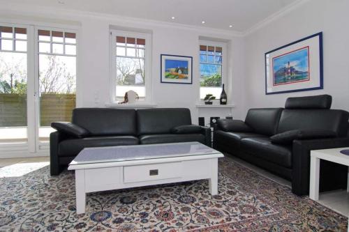 a living room with two black couches and a coffee table at Maybachstraße 22 in Westerland