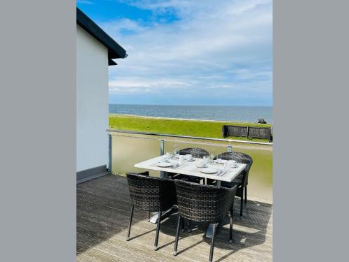 a table and chairs on a balcony with the ocean at Apartment Priwall Teichhof Fehmarn in Wenkendorf