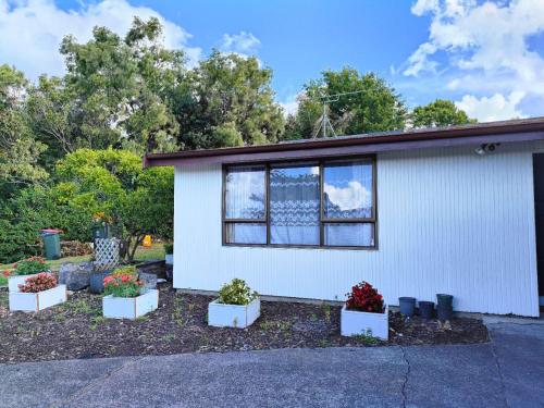a white house with potted plants in front of it at Comfortable stay in Auckland