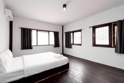 a bedroom with a bed with white sheets and windows at xx Mitr Inn Khaosan - มิตร อินน์ ข้าวสาร in Bangkok