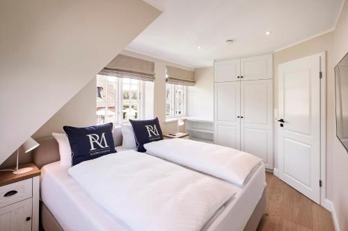 a bedroom with a large white bed with blue pillows at Reethaus Friesenjung in Hedehusum